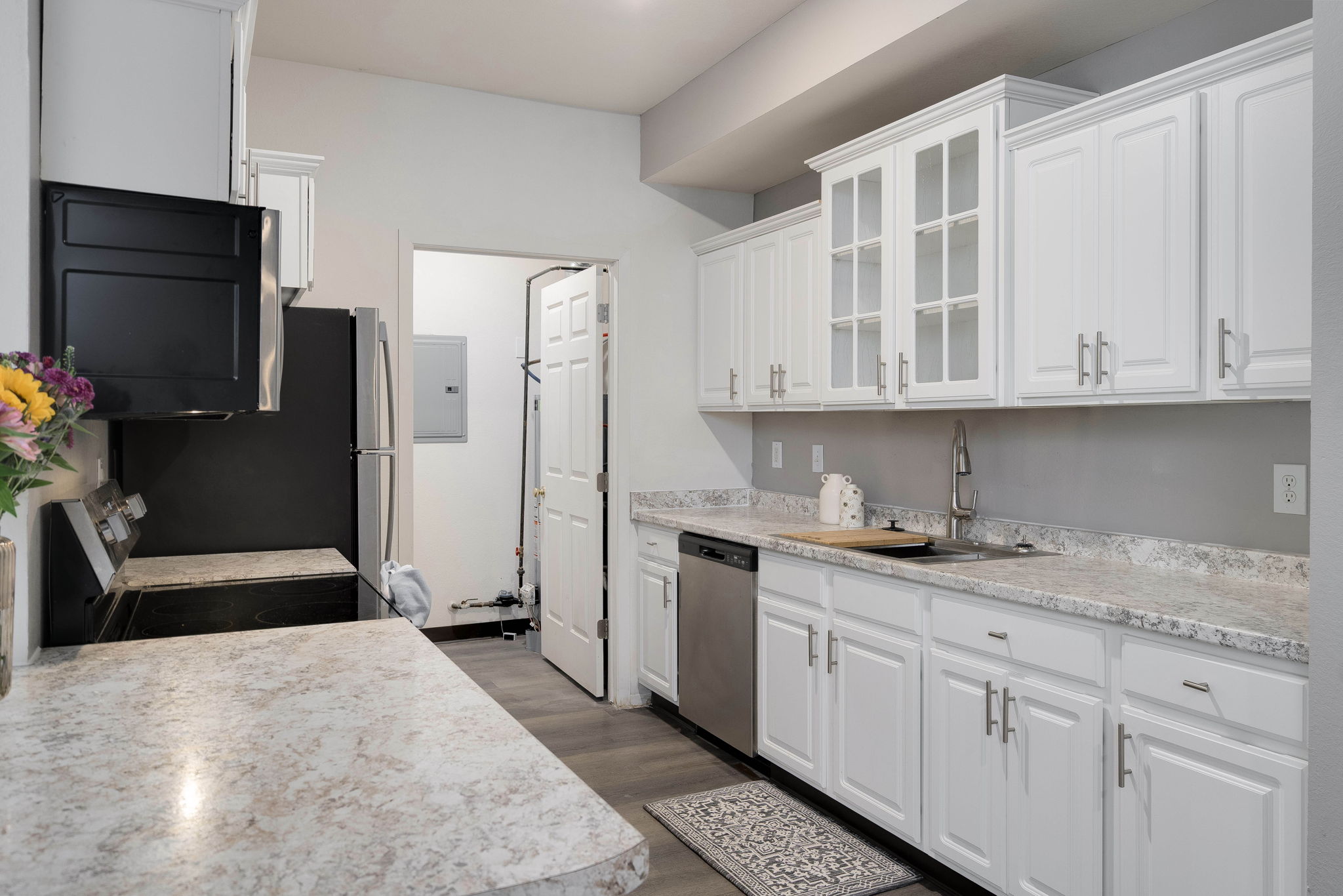 A kitchen with white cabinets and a marble countertop.